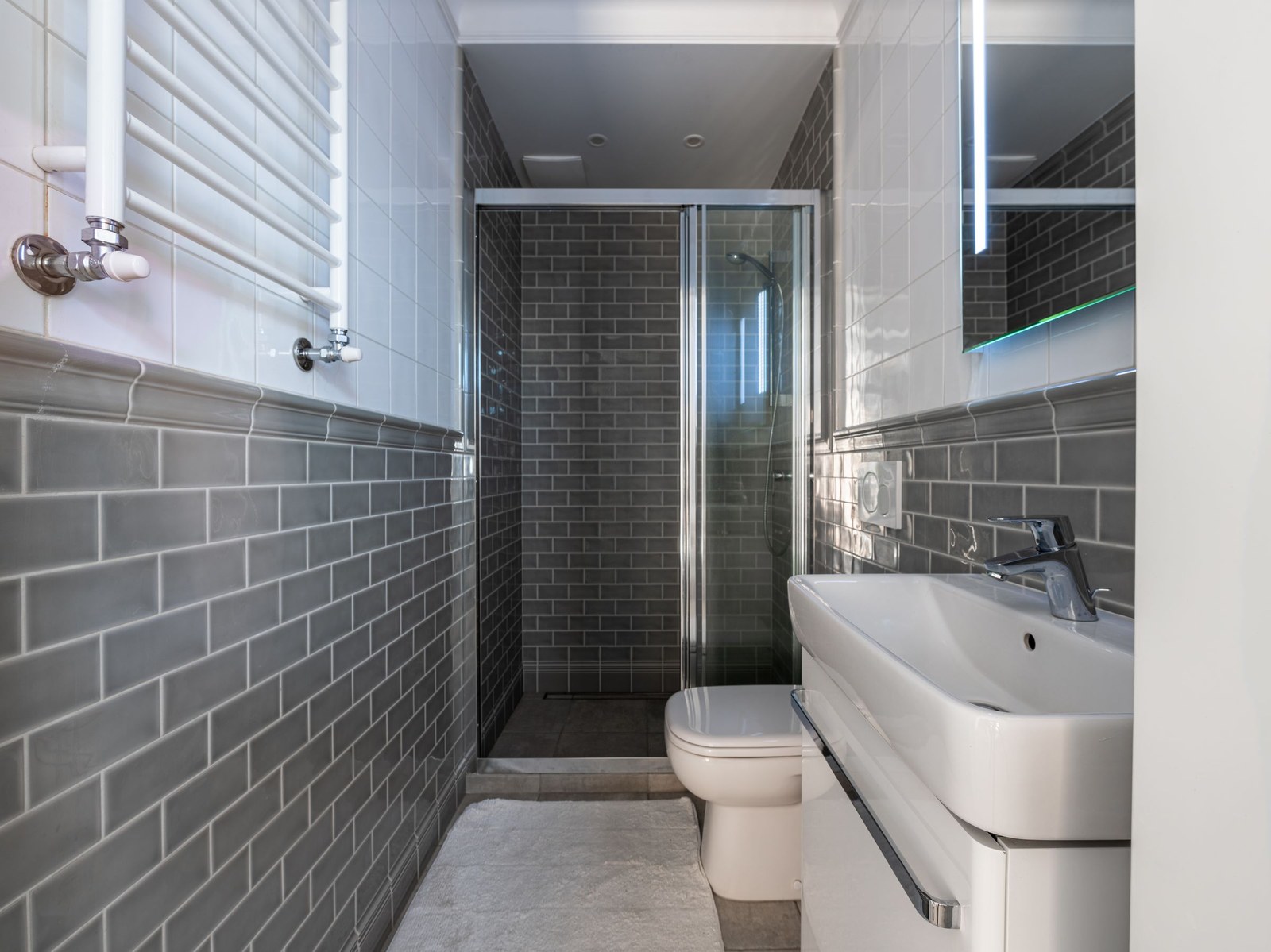Compact bathroom with grey wall tiles and a glass shower screen, sanitaryware for new builds