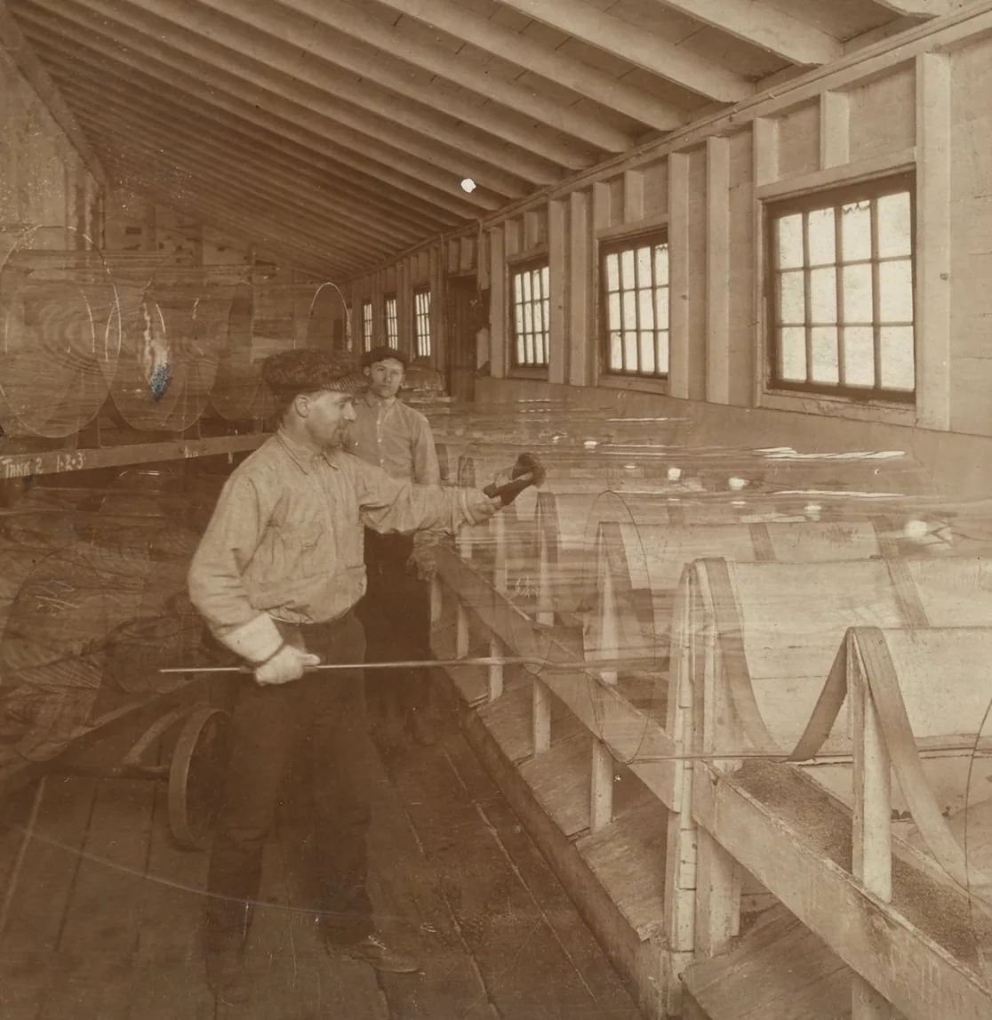 Glassworker splitting blown glass cylinders before they are flattened into sheets