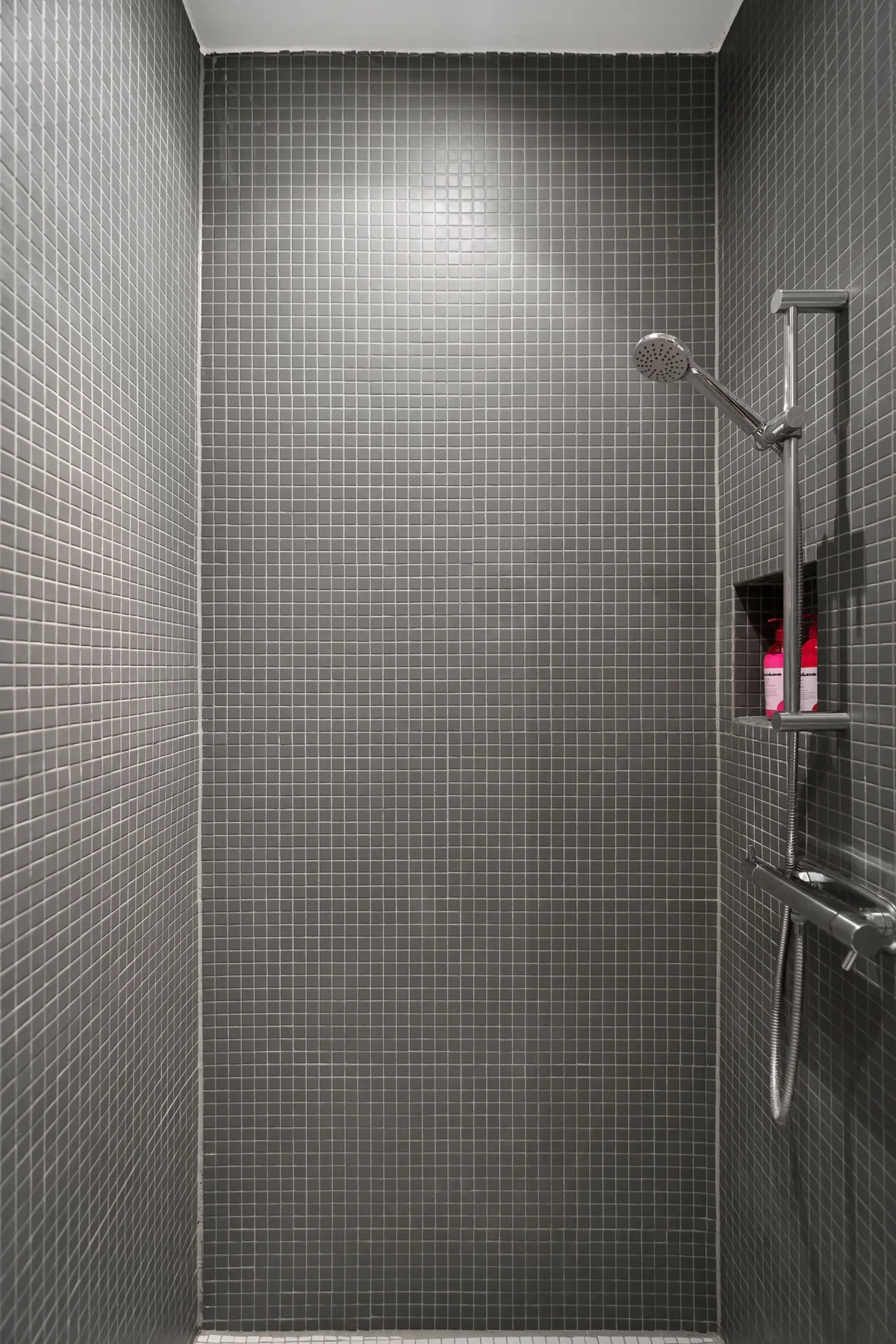 Grey mosaic tiles in a walk-in shower with a hand shower and thermostatic mixer