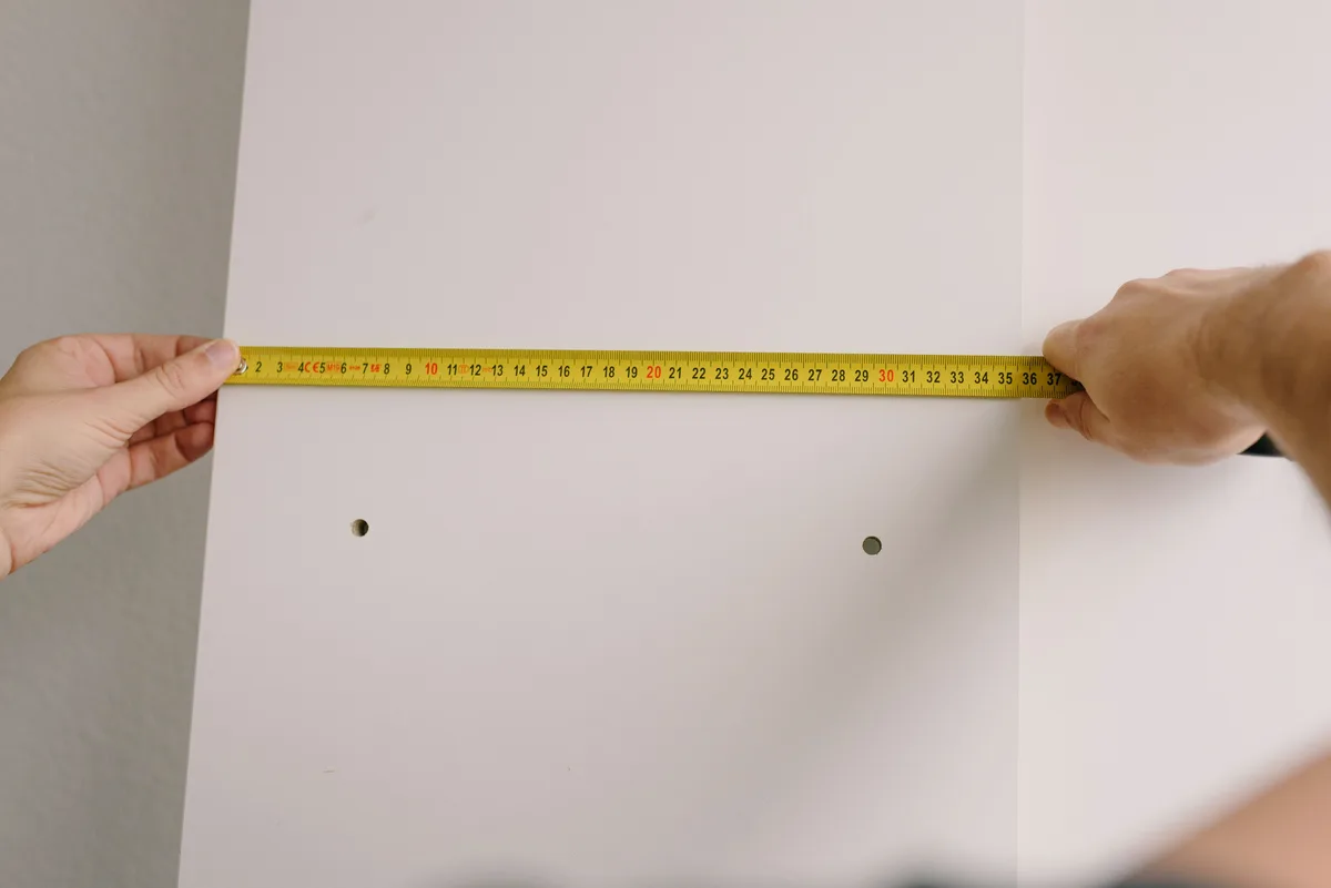 Rolmaat horizontaal tegen een witte wand met twee geboorde gaten eronder
