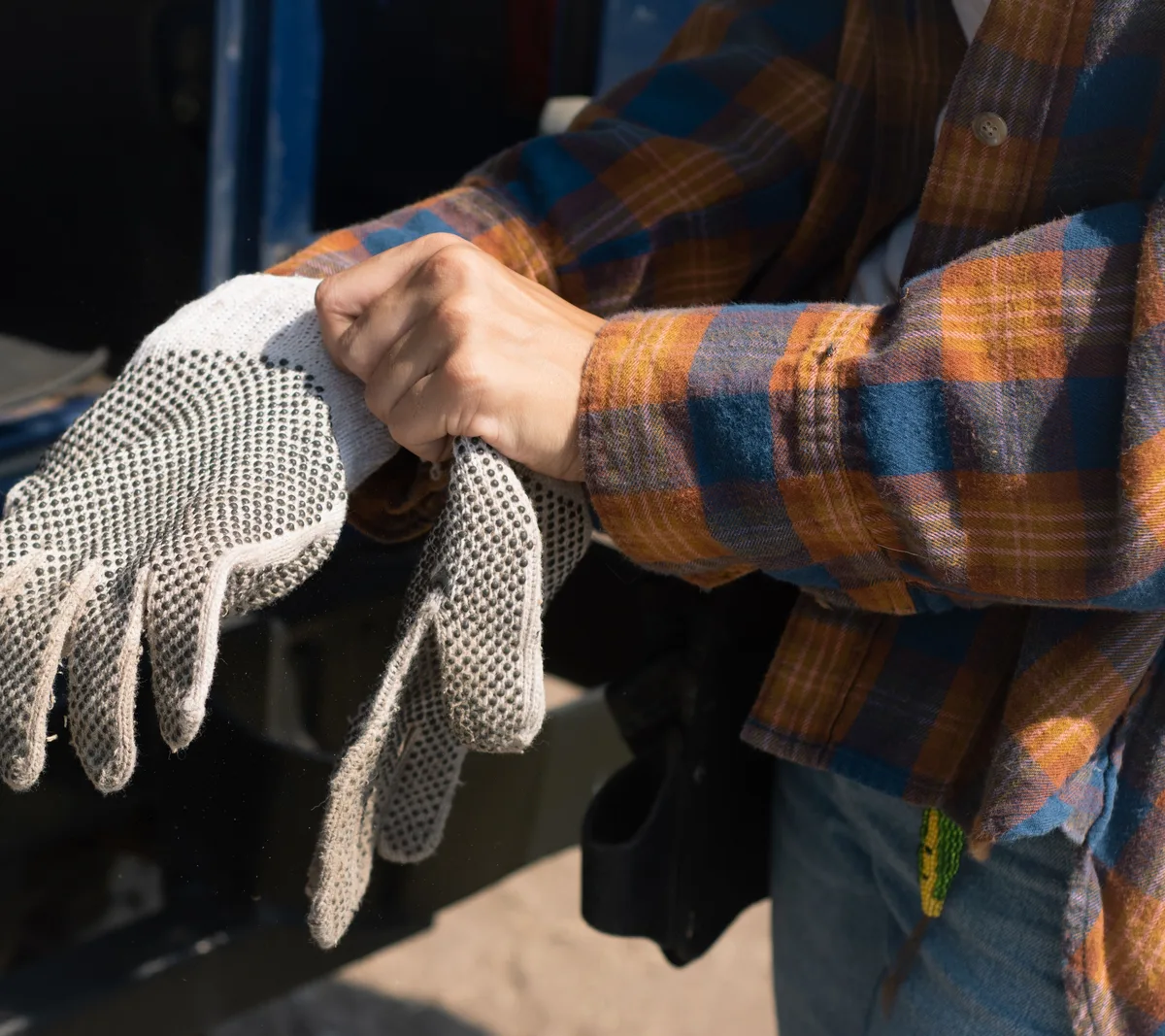 Man putting on grey knitted work gloves with dots