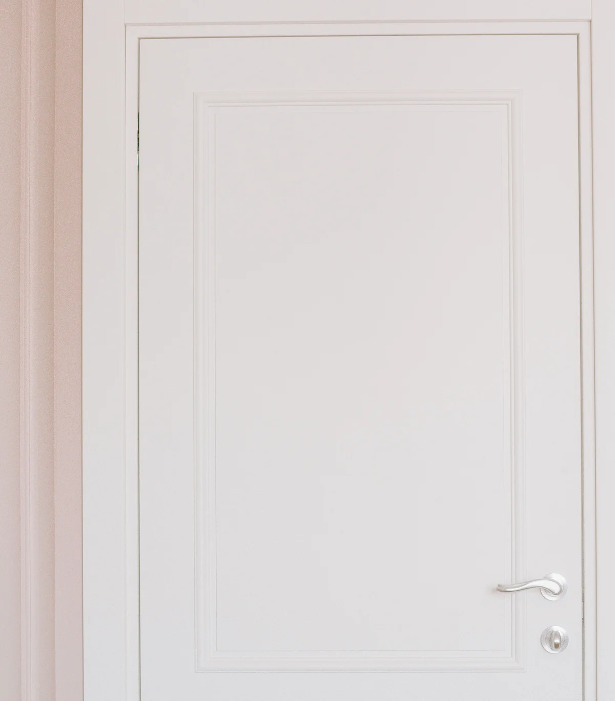 A white interior door with a panelled profile and a door handle