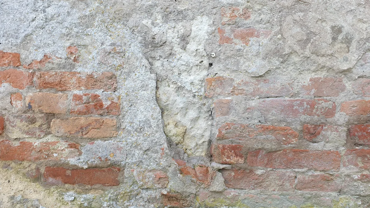 An old brick wall with partly crumbled plaster