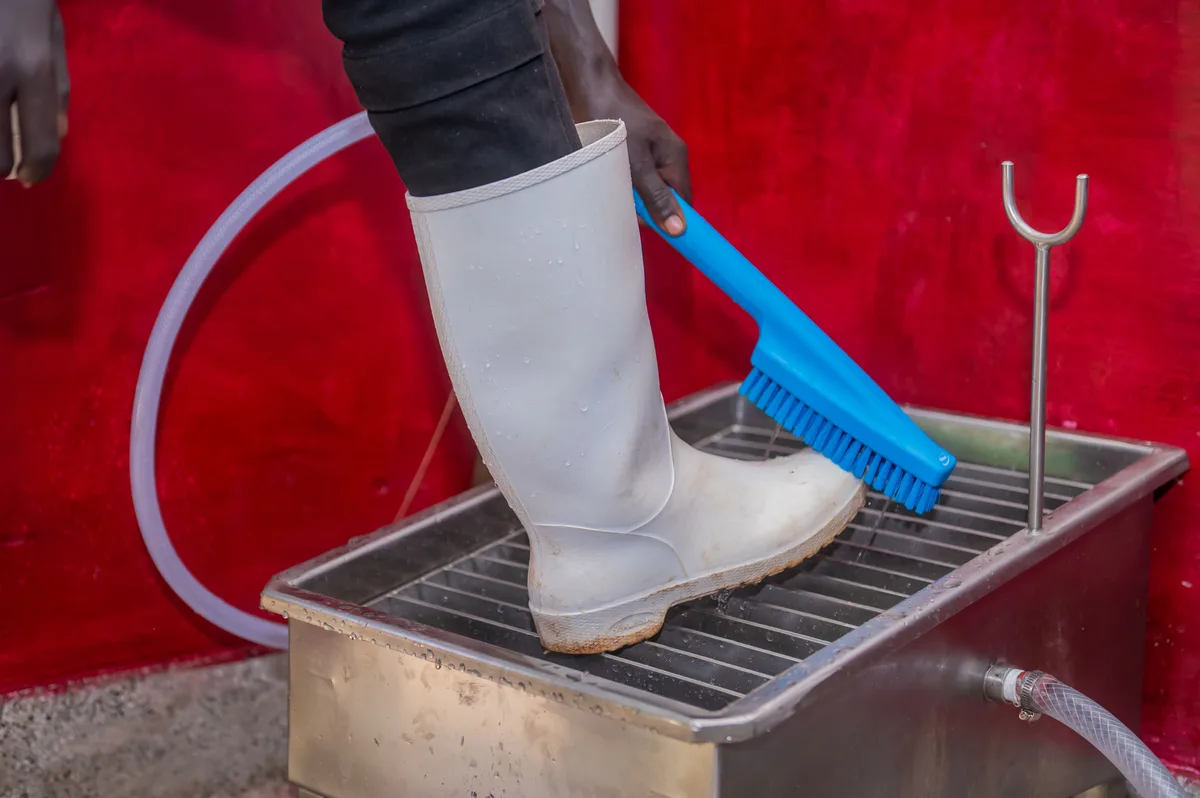 Witte rubberlaars wordt met een borstel schoongemaakt bij een laarzenwasplaats