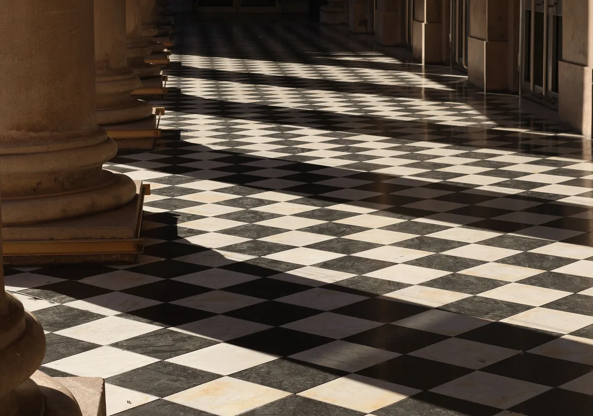 Black and white tiled floor laid diagonally in a checkerboard pattern in a colonnade