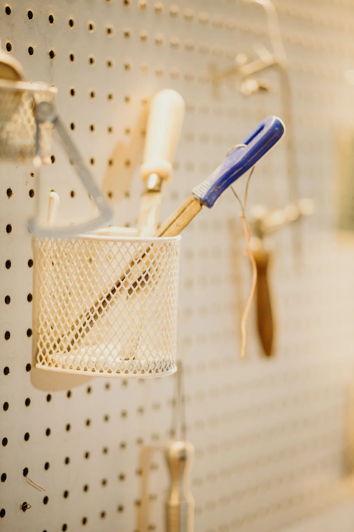 A perforated tool board with a mesh basket holding tools