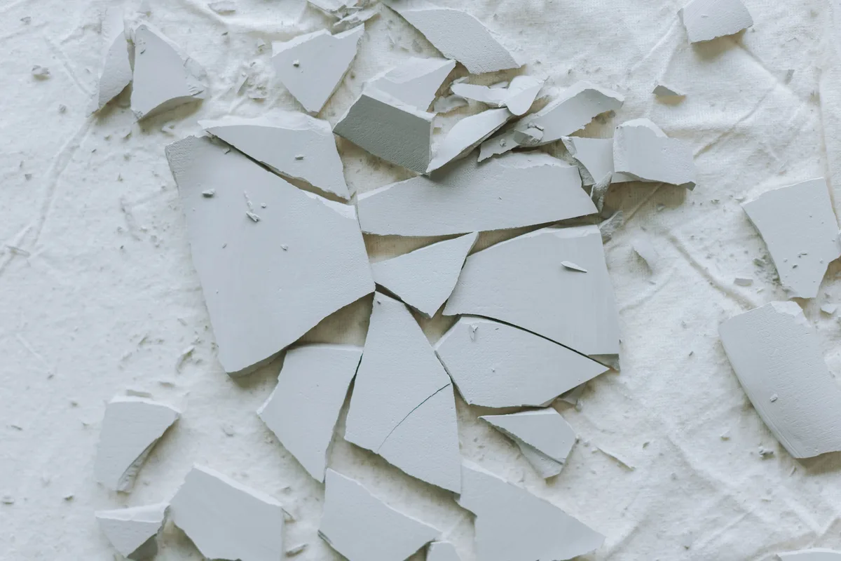 Shards of a broken light grey tile on a white cloth
