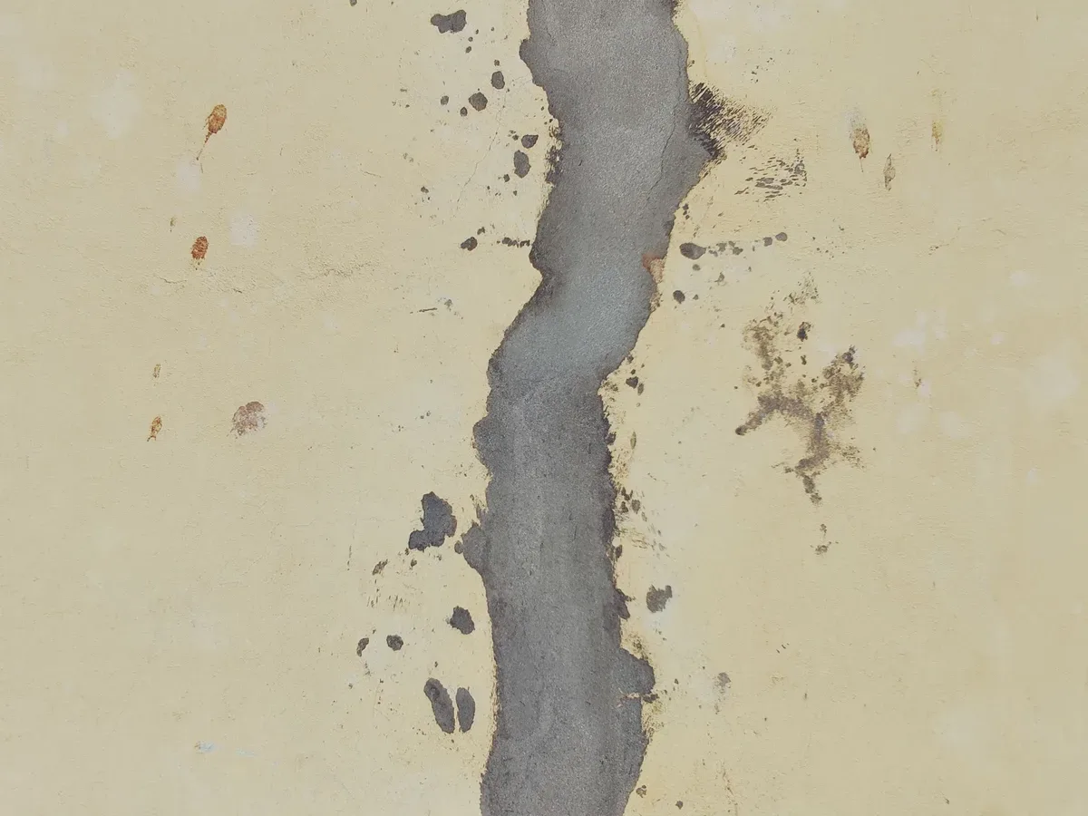 Crack in a light-coloured wall filled with grey mortar