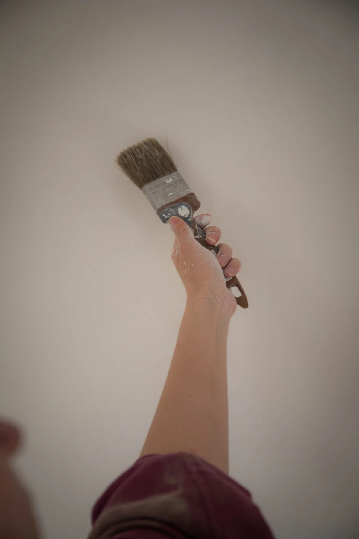 Hand met een kwast werkt een lichte muur bij