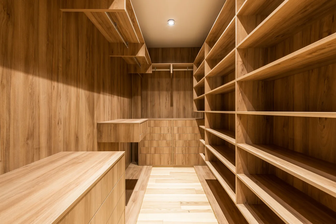 A wooden walk-in closet with shelves, hanging space and a drawer unit