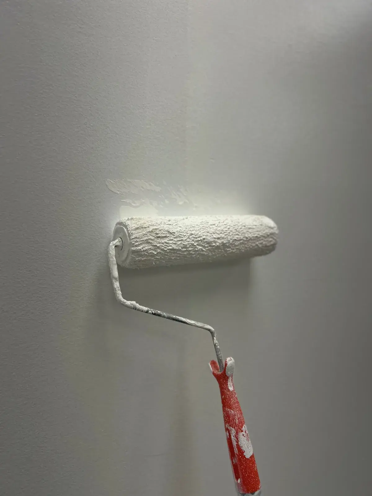 Verfroller op een lichtgrijze muur tijdens het schilderen