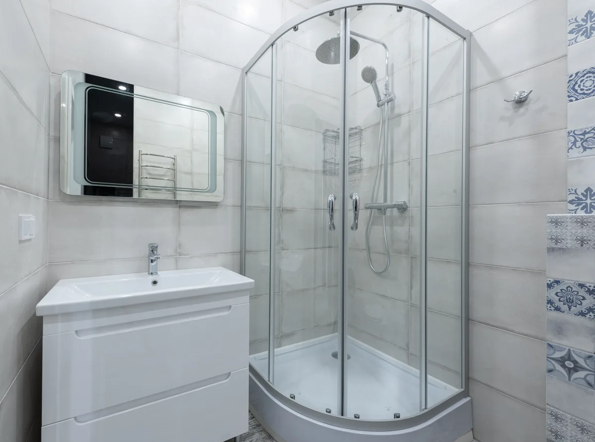 Small bathroom with a quadrant shower enclosure with thermostatic tap, a white vanity unit and a mirror