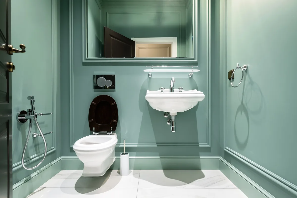Groene toiletruimte met hangtoilet en donkere houten toiletzitting