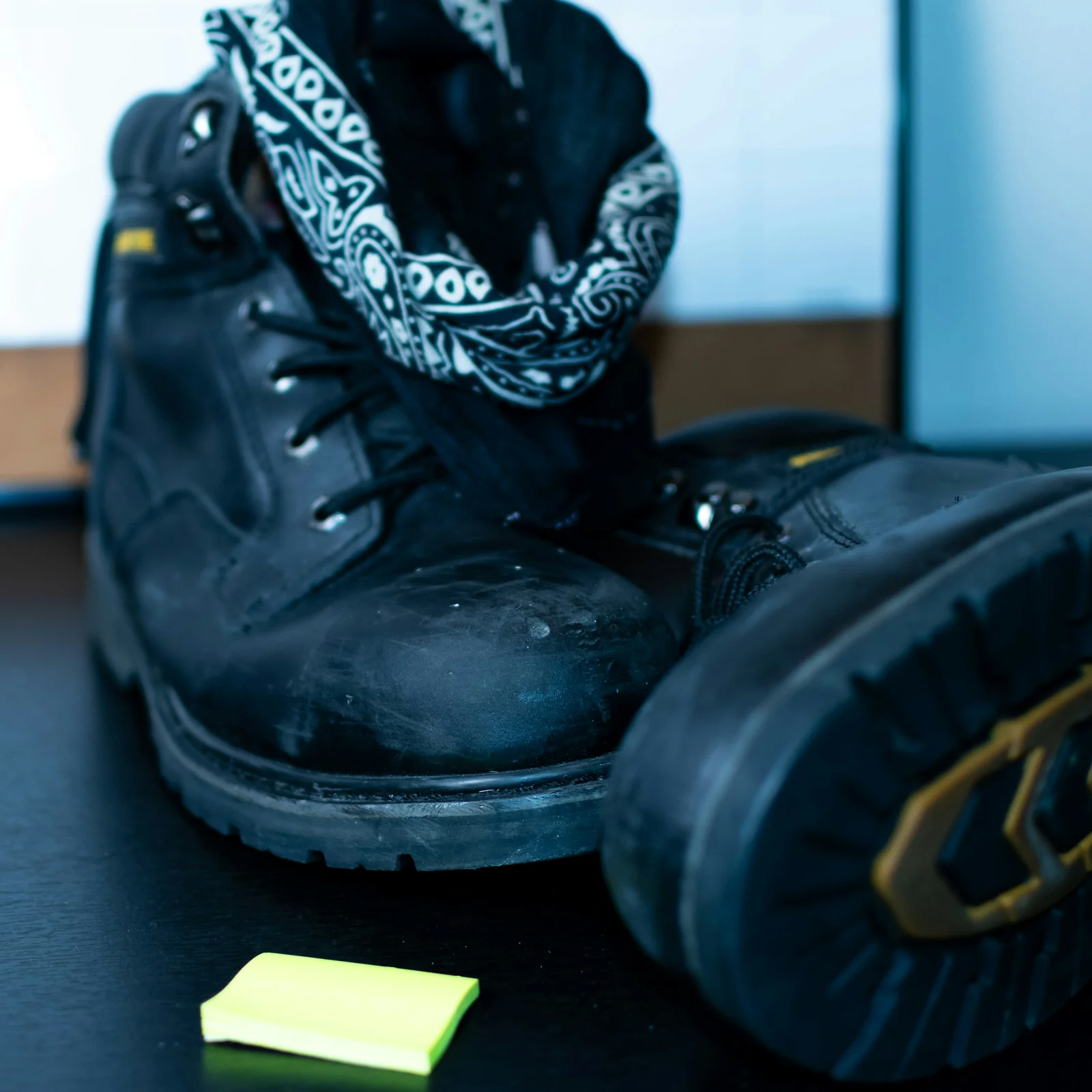 Worn black leather work boots with visible wear on the toe and sole