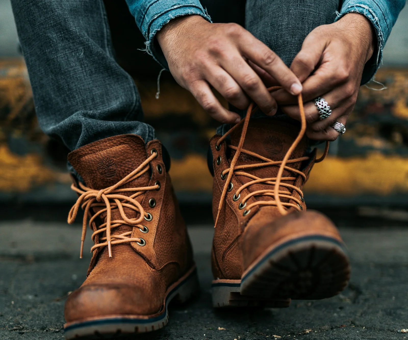 Someone tying the laces of high brown leather lace-up boots