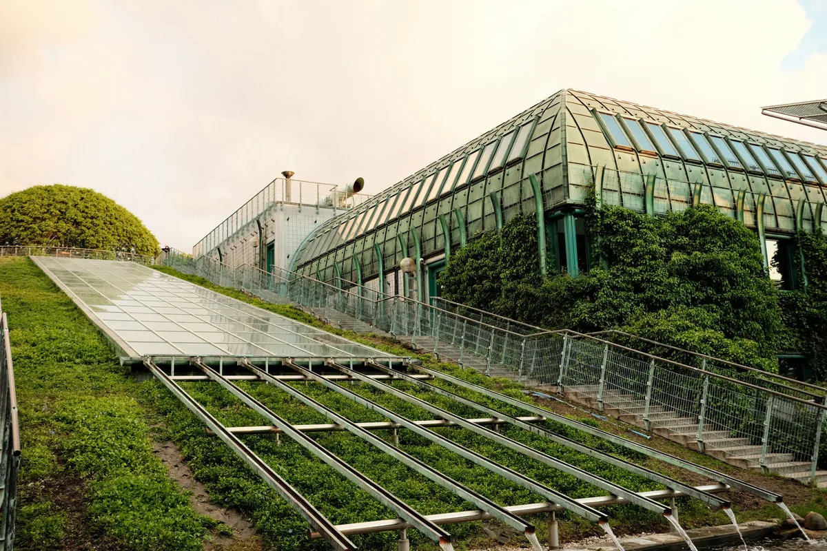 Building with a green roof and a glass canopy on a grassy hill